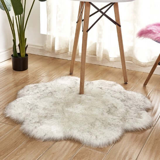 Fluffy artificial woolen carpet rug in a flower shape placed under a wooden table, enhancing room decor.