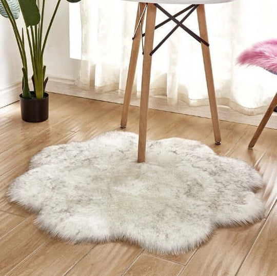 Fluffy artificial woolen carpet rug in a flower shape placed under a wooden table, enhancing room decor.